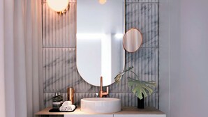 A modern bathroom with a marble vanity, a large mirror, and a small plant. - Gajrash Suites (Baku)