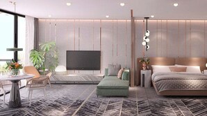 A modern bedroom with a large bed, a TV, a bedside table, and a seating area with a table and chairs. - Gajrash Suites (Baku)