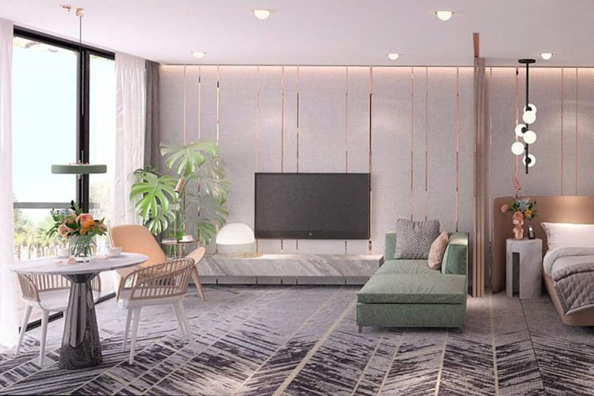 A modern bedroom with a large bed, a TV, a bedside table, and a seating area with a table and chairs.