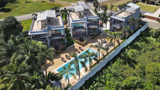 Un hôtel moderne doté d’une piscine, entouré de palmiers et de verdure.