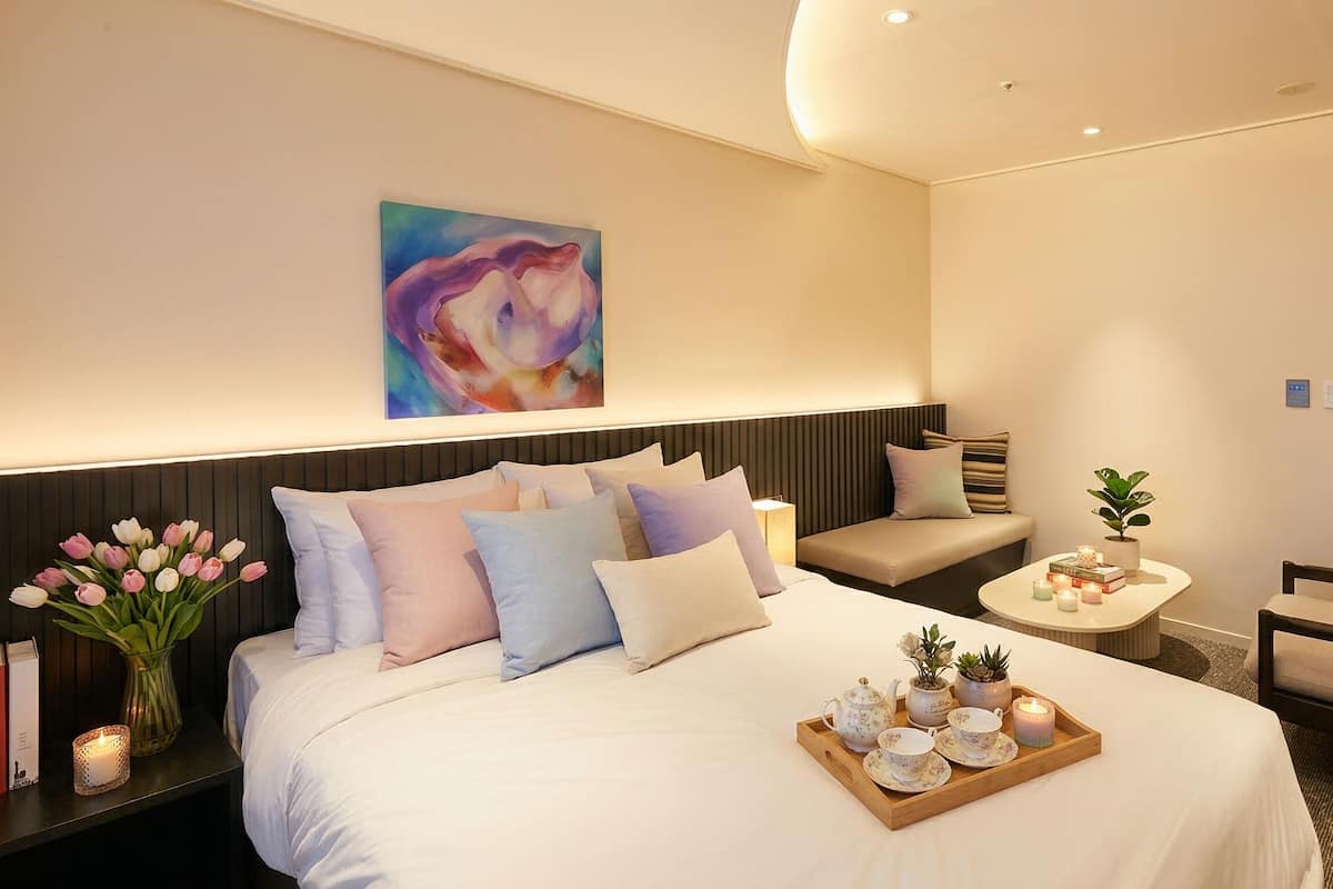 Une chambre d’hôtel avec un lit, une table de chevet, une chaise et un tableau au mur.