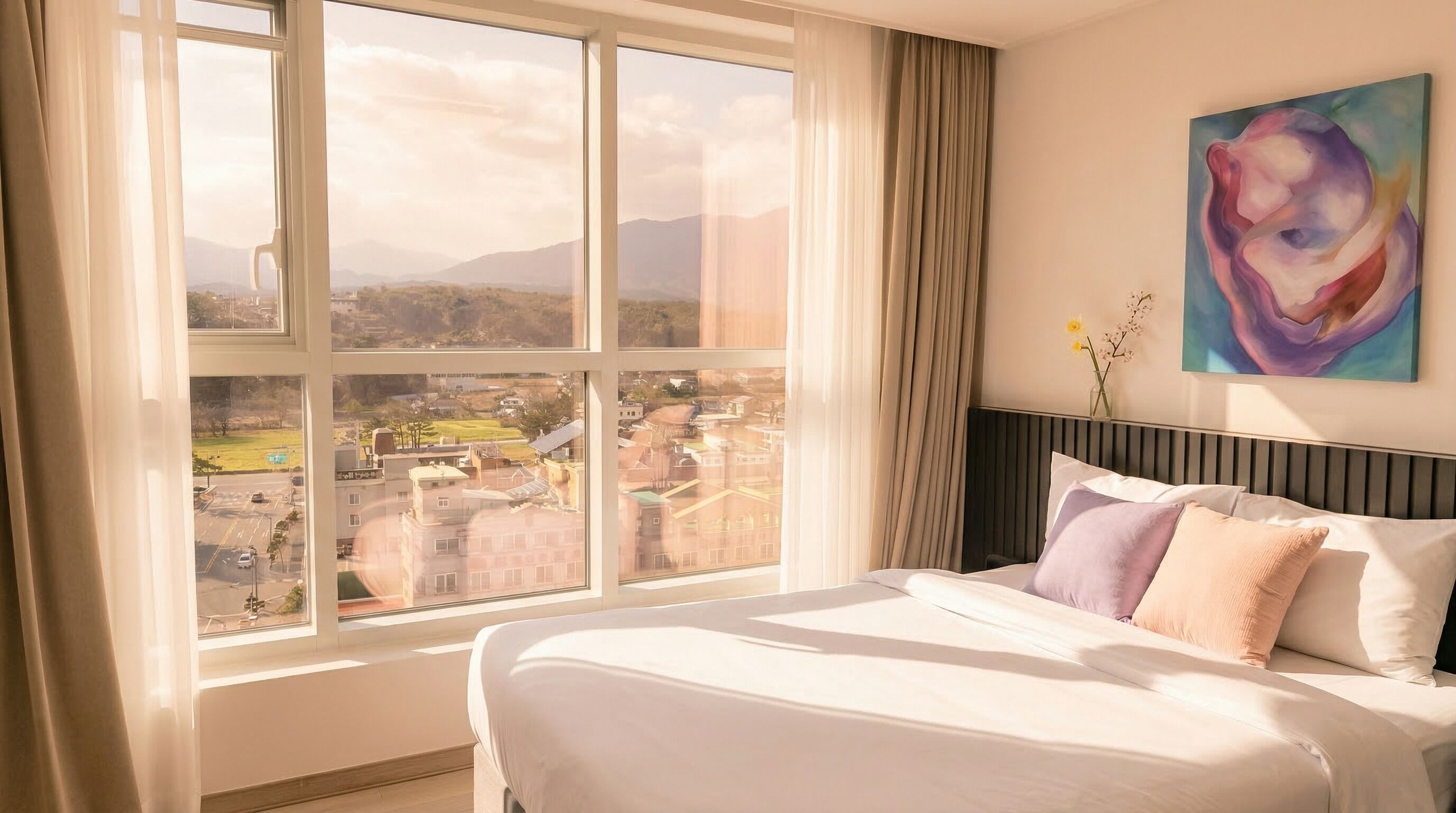 Una habitación de hotel con un ventanal grande, una cama y un cuadro en la pared.