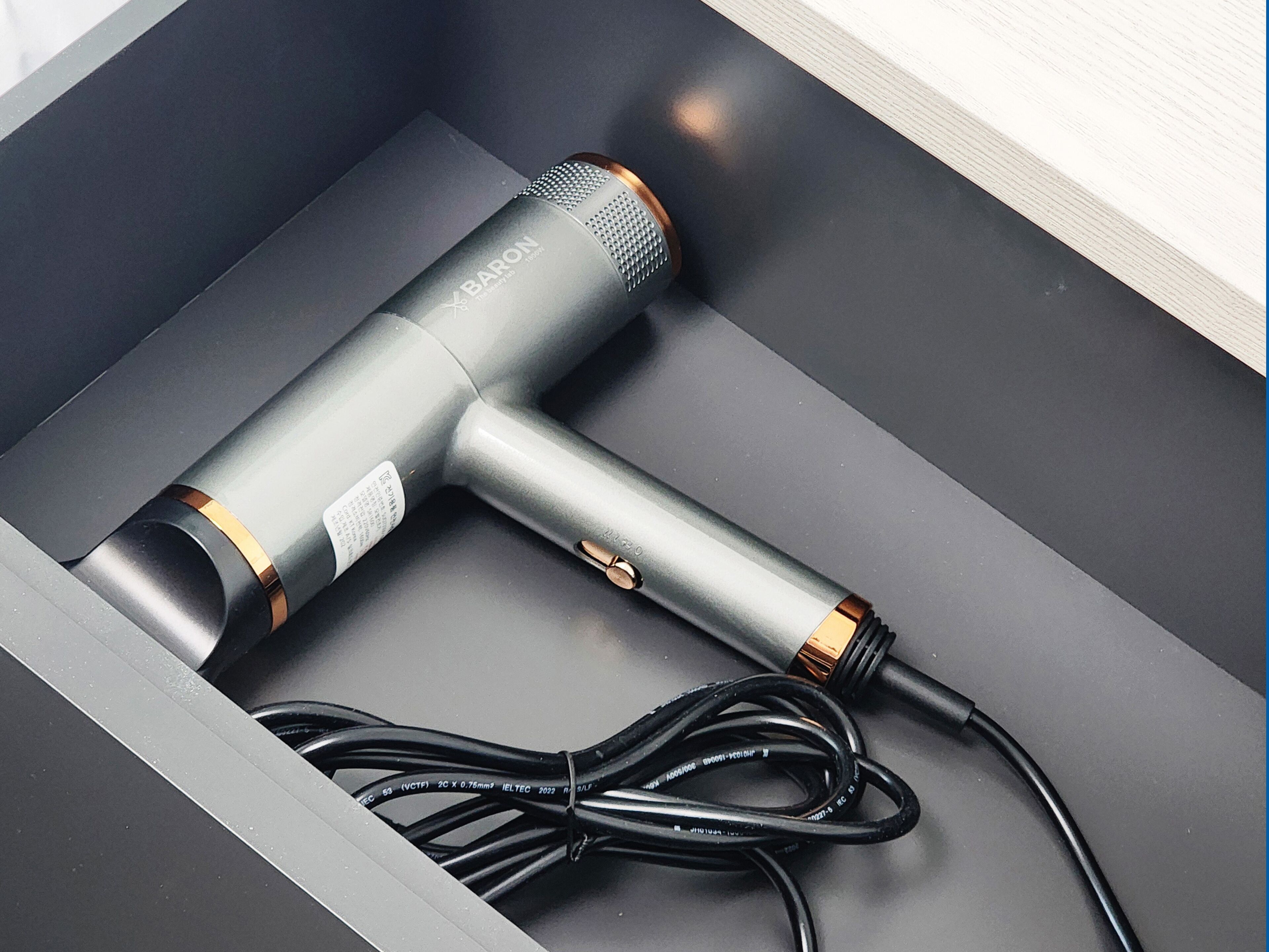 A hair dryer with a cord inside a drawer.