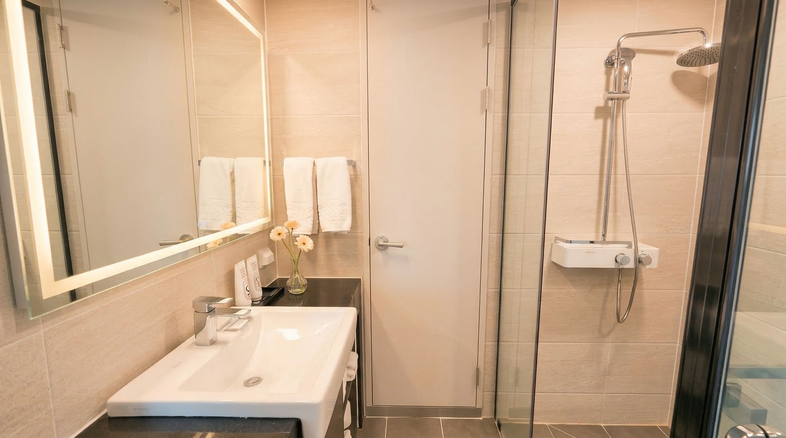 A bathroom with a glass-enclosed shower, a sink, and a mirror.