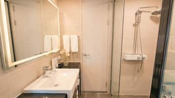 A bathroom with a glass-enclosed shower, a sink, and a mirror.