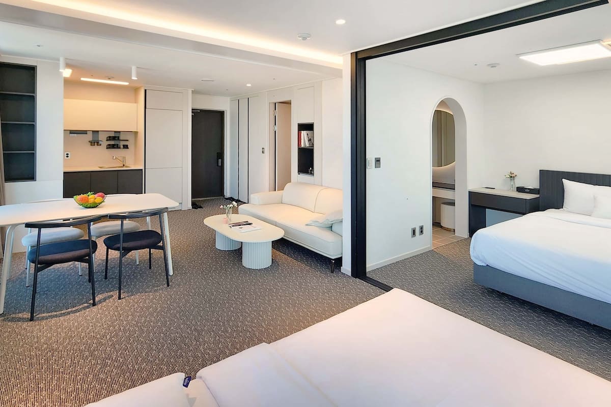 Une chambre d’hôtel moderne équipée d’un lit, d’un bureau avec une chaise, d’un canapé et d’un petit coin cuisine.