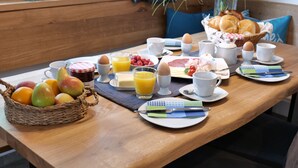 Une table de petit-déjeuner dressée avec divers aliments, notamment des fruits, des œufs et des boissons.