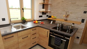 Une cuisine moderne dotée d’un plan de travail en granit, de meubles en bois, d’un four encastré et d’un pare-feu en pierre.