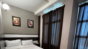 A neatly made bed with white linens and towels, a dark headboard, and two framed pictures on the wall. - HOTEL ECONOMY KAPAR (Kapar)