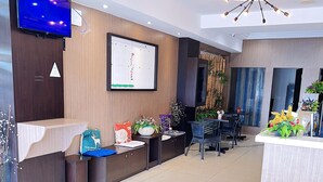 A modern reception area with a flat-screen TV, a large framed chart, and a decorative ceiling light. - HOTEL ECONOMY KAPAR (Kapar)
