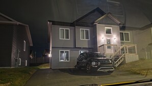 Une maison à deux étages avec une allée, un escalier et un véhicule garé devant.