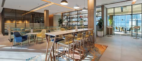 A modern interior with a bar area, seating, and a view through large windows.