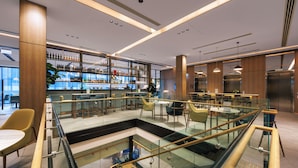 A modern interior with a bar area, seating, and a glass-walled staircase.