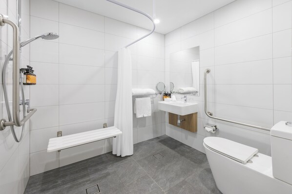 A modern bathroom with a shower, toilet, sink, and bench.