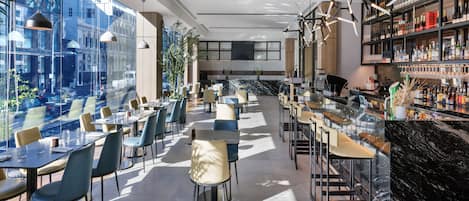 A modern bar area with seating and a view of the city.