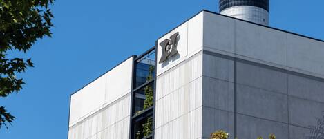 A modern building with a prominent tower, a glass facade, and a clear blue sky.