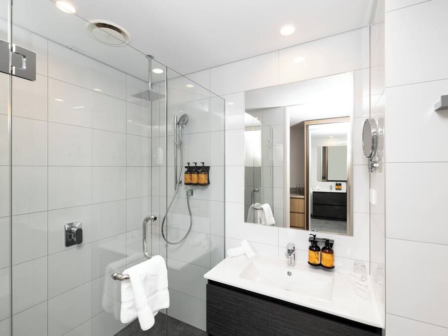 A modern bathroom with a glass-enclosed shower, a vanity with a mirror, and a towel rack.