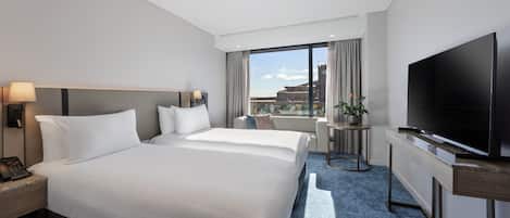 Habitación de hotel con una cama grande, televisión, escritorio y vistas a la ciudad.