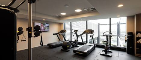 Une salle de sport équipée de tapis de course, d’un vélo d’appartement et d’un banc de musculation.