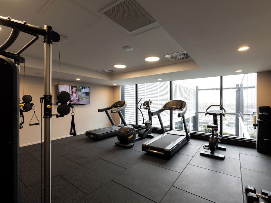 Une salle de sport équipée de tapis de course, d’un vélo d’appartement et d’un banc de musculation.
