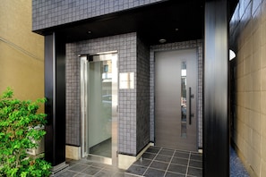 A modern building entrance with a glass door, a metal gate, and a tiled floor. - Asakusa Landing (Tokyo)