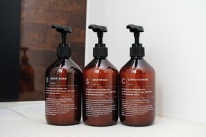 Three bottles of body soap, shampoo, and conditioner on a shelf. - Asakusa Landing (Tokyo)