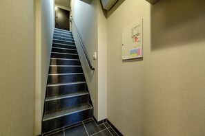 A staircase with a handrail, a wall-mounted information board, and a light switch. - Asakusa Landing (Tokyo)