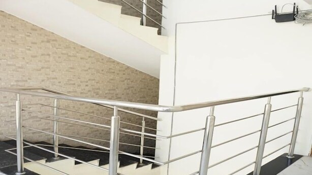 Eine moderne Treppe mit Metallgeländer, einer Ziegelwand und einer weißen Wand mit schwarzem Lichtschalter.