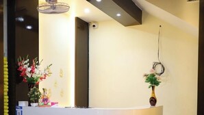 Ein Empfangsschalter mit weißer Theke, Deckenventilator und eine Vase mit Blumen.