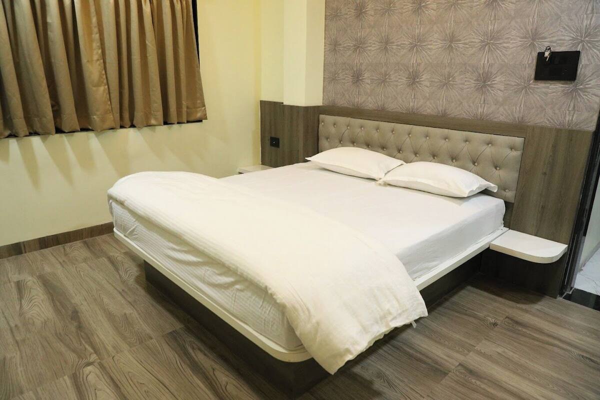 A neatly made bed with a wooden headboard, a bedside table, and a wall-mounted light fixture.