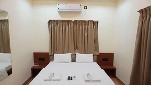 Ein Hotelzimmer mit Bett, zwei Nachttischen, einer Klimaanlage und Vorhängen.