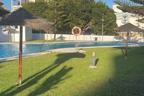 A swimming pool with a lifebuoy, thatched umbrellas, and a grassy area. - Holiday home in Almeria (Almeria)