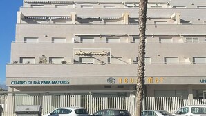 A multi-story building with a sign reading "CENTRO DE DIÁ PARA MAYORES" and "NEUMAT UN".