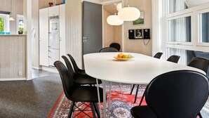A modern dining area with a white table, black chairs, and a red patterned rug.