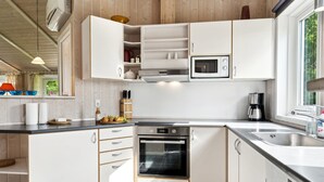 A modern kitchen with white cabinetry, a built-in oven, a microwave, and a coffee maker.