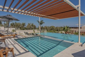 A pool area with a pergola, lounge chairs, and a table.