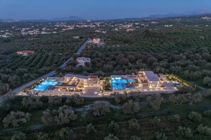 An aerial view of a resort with multiple swimming pools, a well-maintained landscape, and a variety of buildings.