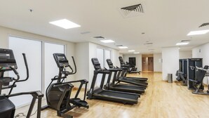 Une salle de sport équipée de tapis de course et d’appareils elliptiques disposés en rangées.