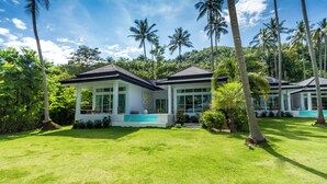 A modern house with a large lawn, surrounded by palm trees and lush greenery. - Coastal Escape Koh Yao Noi (Ko Yao)