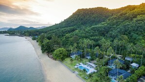 An aerial view of a coastal resort with a beachfront, lush greenery, and multiple villas with swimming pools. - Coastal Escape Koh Yao Noi (Ko Yao)