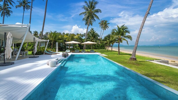 A swimming pool with a wooden deck, surrounded by palm trees and a beach view. - Coastal Escape Koh Yao Noi (Ko Yao)