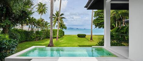 A modern outdoor pool area with a clear view of the ocean and distant islands.