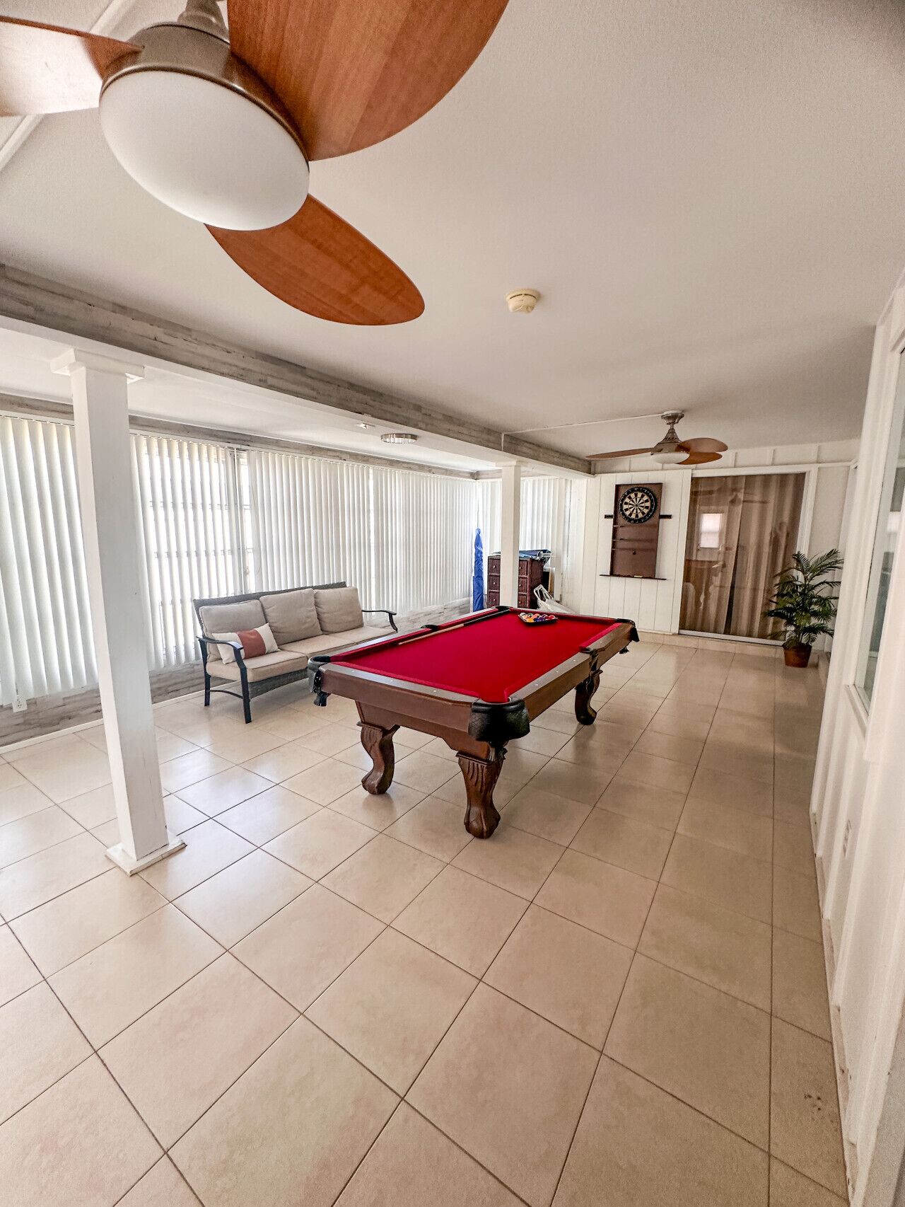 A spacious room with a pool table, a sofa, and a ceiling fan.