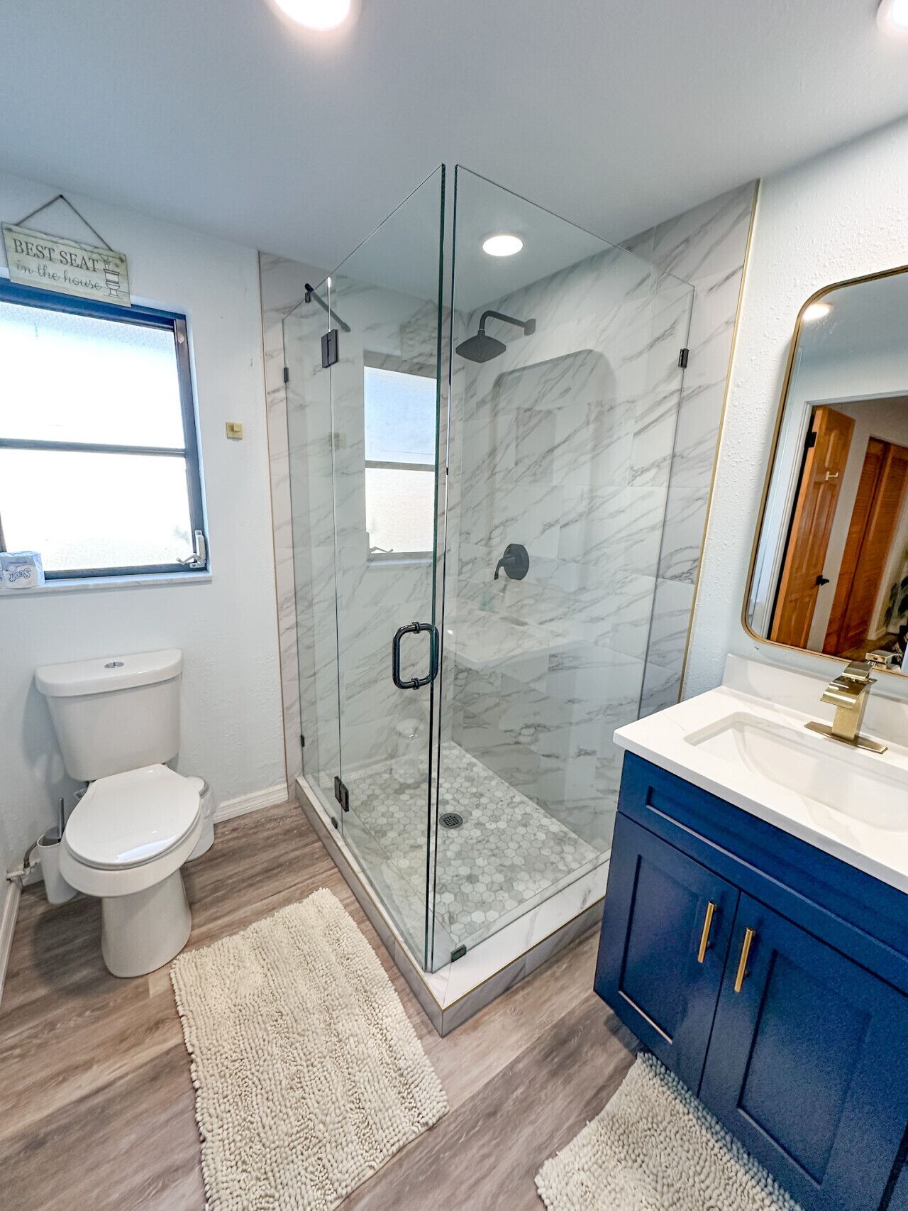 Un baño moderno con ducha de vidrio, inodoro y tocador con espejo.