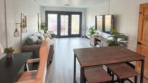 Un amplio salón con sofá, mesa de comedor y televisor.