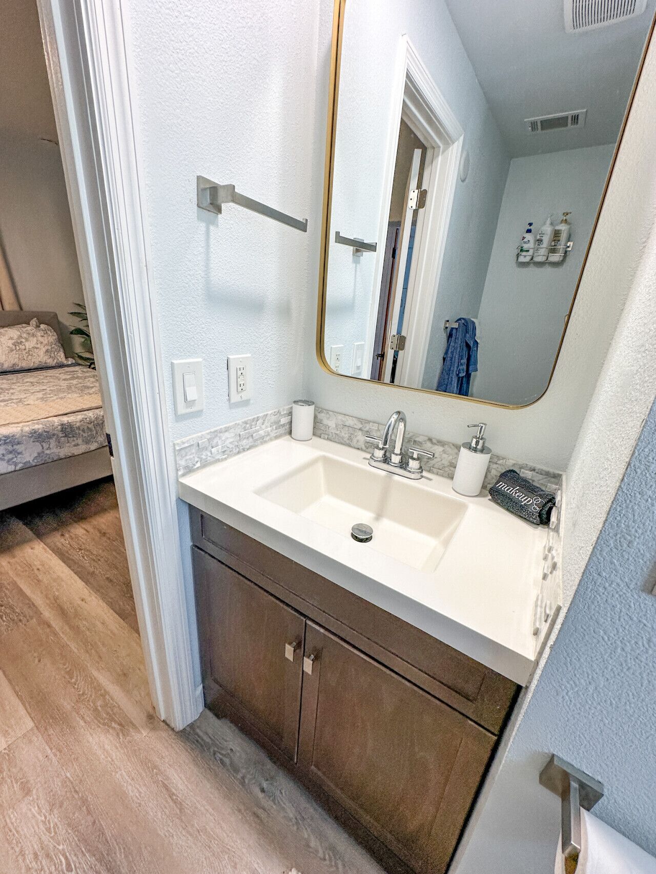 A bathroom with a white sink, a mirror, and a towel.