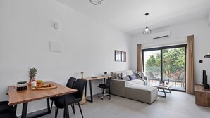Un salon moderne comprenant un coin repas, un canapé et un meuble pour la télévision.