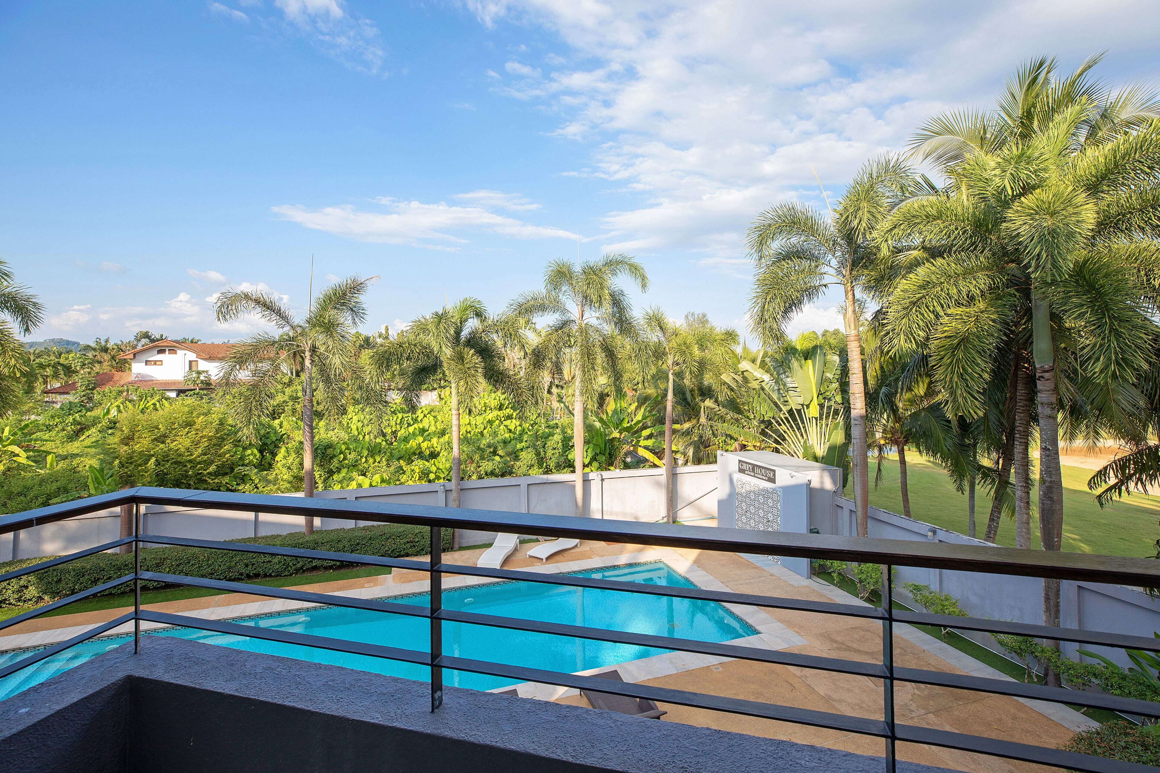 Una piscina con vistas a palmeras y una casa distante.