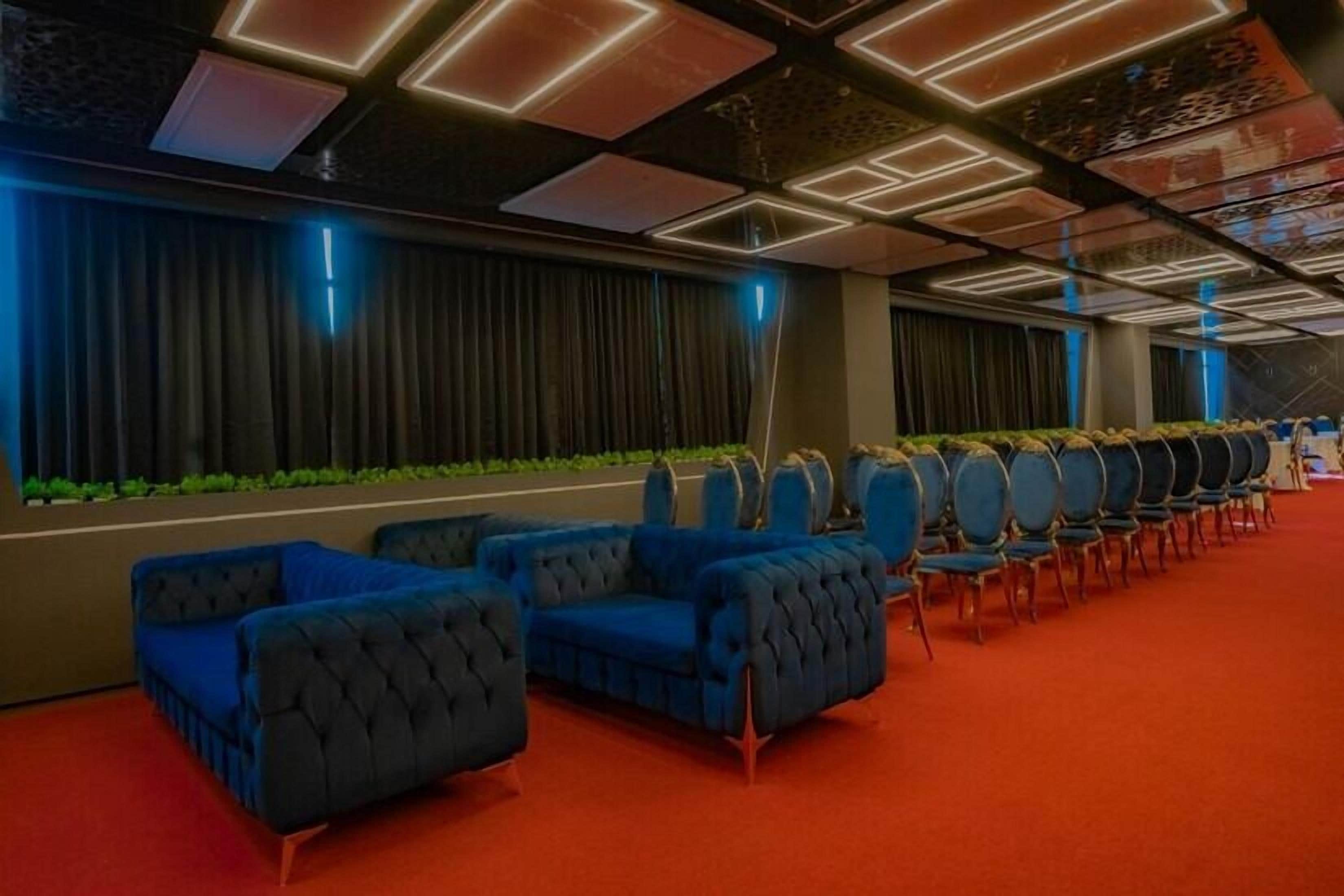 A hotel lobby with a red carpet, blue sofas, and a row of round tables.