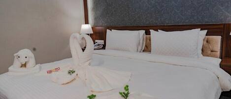 A hotel room with a neatly made bed, a lamp on the nightstand, and a towel rack with towels.